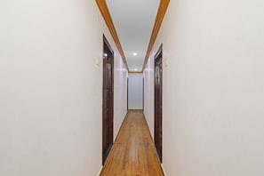 Un pasillo estrecho con suelo de madera y puertas a ambos lados.