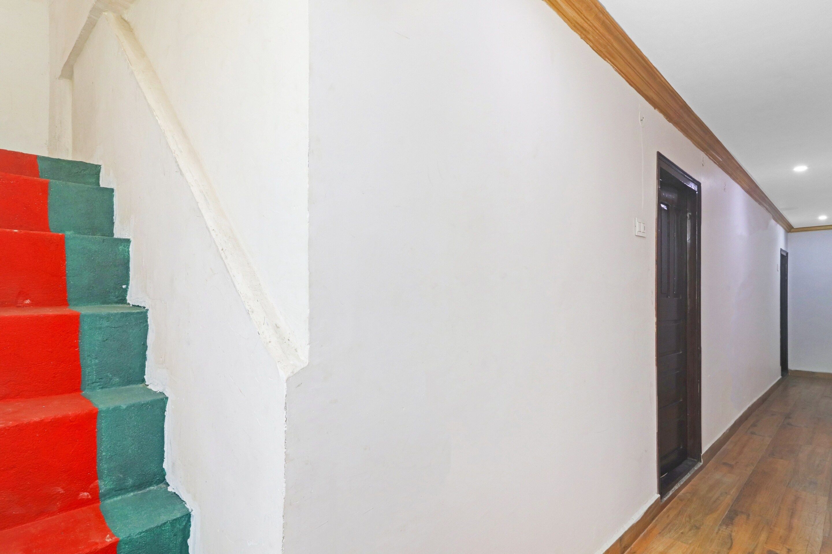 Una escalera con peldaños rojos y verdes que conduce a una puerta oscura.