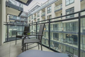 A modern apartment with a glass balcony, furnished with wicker chairs and a small table. - Comfortable Apartment in Warsaw with Workspace by Noclegi Renters (Warszawa)