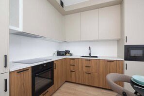 A compact kitchen with a built-in oven, a microwave, and a coffee maker. - Comfortable Apartment in Warsaw with Workspace by Noclegi Renters (Warszawa)
