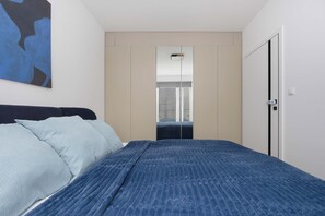A bedroom with a bed, a wardrobe, and a mirror. - Comfortable Apartment in Warsaw with Workspace by Noclegi Renters (Warszawa)