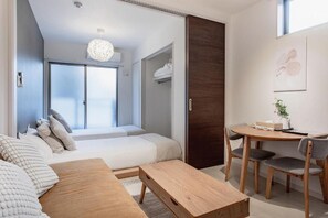 A modern bedroom with a bed, a wooden table, and a chair. - Tabi Time Gangtian Imazato (Osaka, Ikuno-ku)