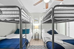 A room with bunk beds, a nightstand with a lamp, and a ceiling fan. - Roomy and Modern Apartment | Near AT&T Stadium (Arlington)