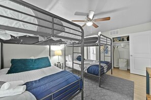 A bunk bed room with a ceiling fan, a bedside table with a lamp, and a small window. - Roomy and Modern Apartment | Near AT&T Stadium (Arlington)