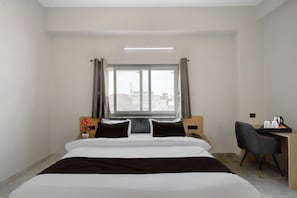 A hotel room with a bed, a desk, a chair, a window, and a view of the cityscape. - Townhouse Maha Mrityunjay Temple (Varanasi)