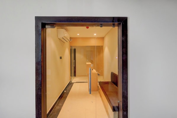 A hallway with a glass door leading to a room with a bed and a desk. - Townhouse Maha Mrityunjay Temple (Varanasi)
