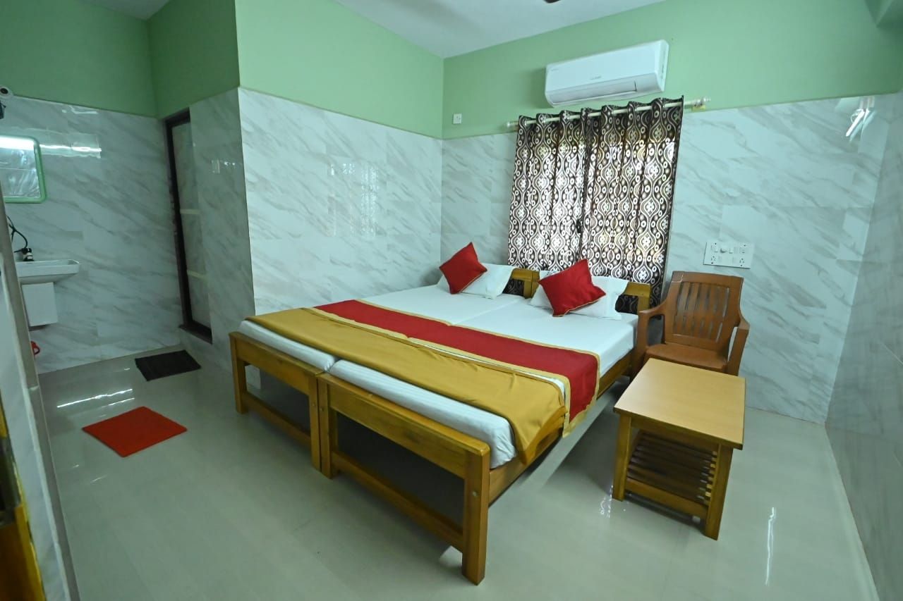 Une chambre d’hôtel avec un lit, un banc en bois, une petite table, un lavabo et une douche.