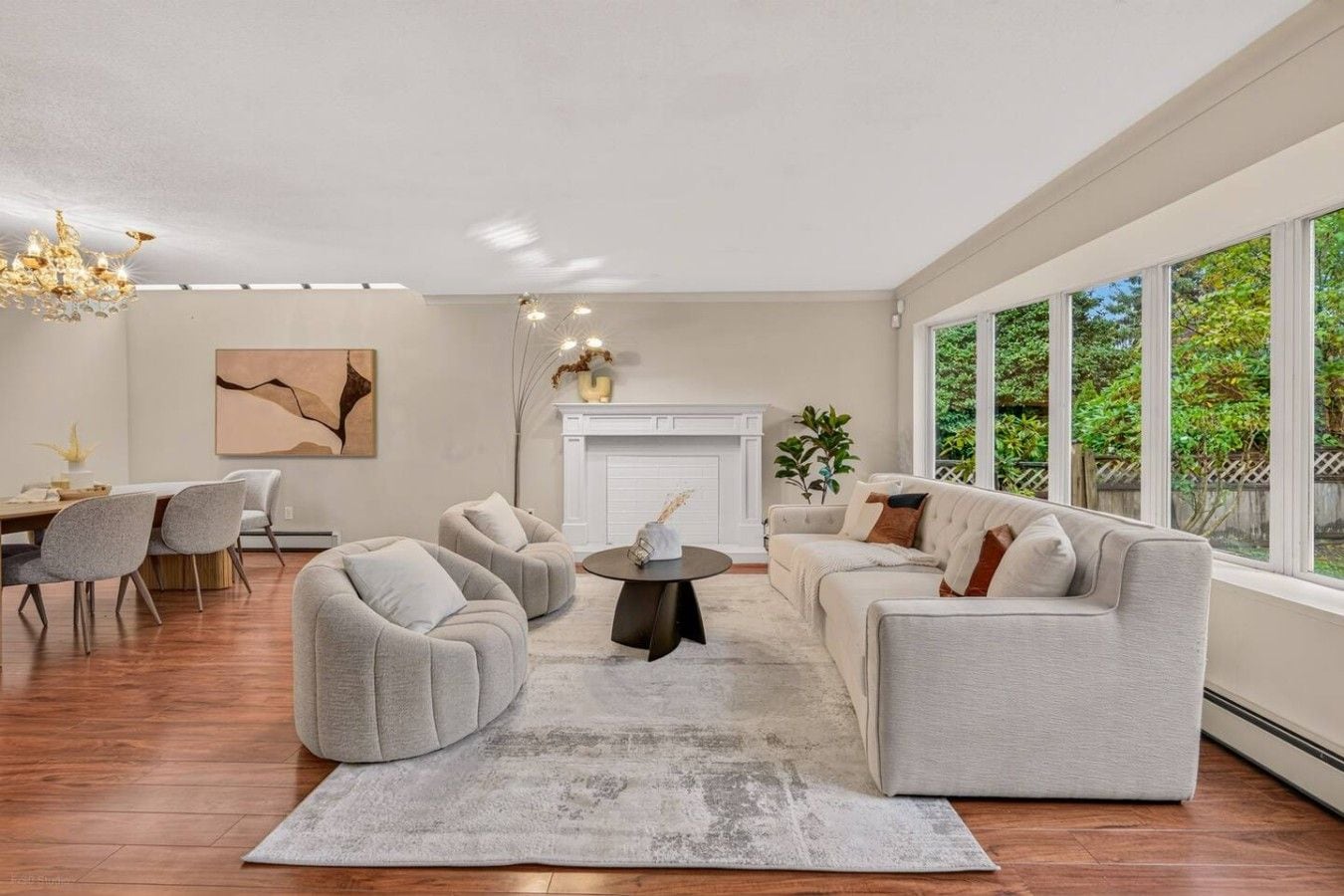 A modern living room with a fireplace, a dining area, and large windows.