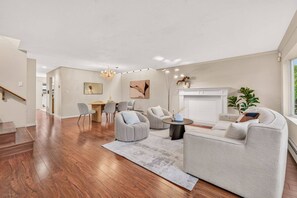 A spacious living room with a fireplace, a dining area, and a staircase leading to another level. - 4BR Family Home | Rooftop Views | UBC & Downtown (Vancouver)