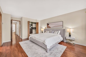 A bedroom with a bed, bedside lamps, a nightstand, a closet, and a hallway. - 4BR Family Home | Rooftop Views | UBC & Downtown (Vancouver)