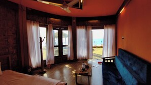 Una habitación con cama, una mesa con objetos, una silla y vistas a la playa.