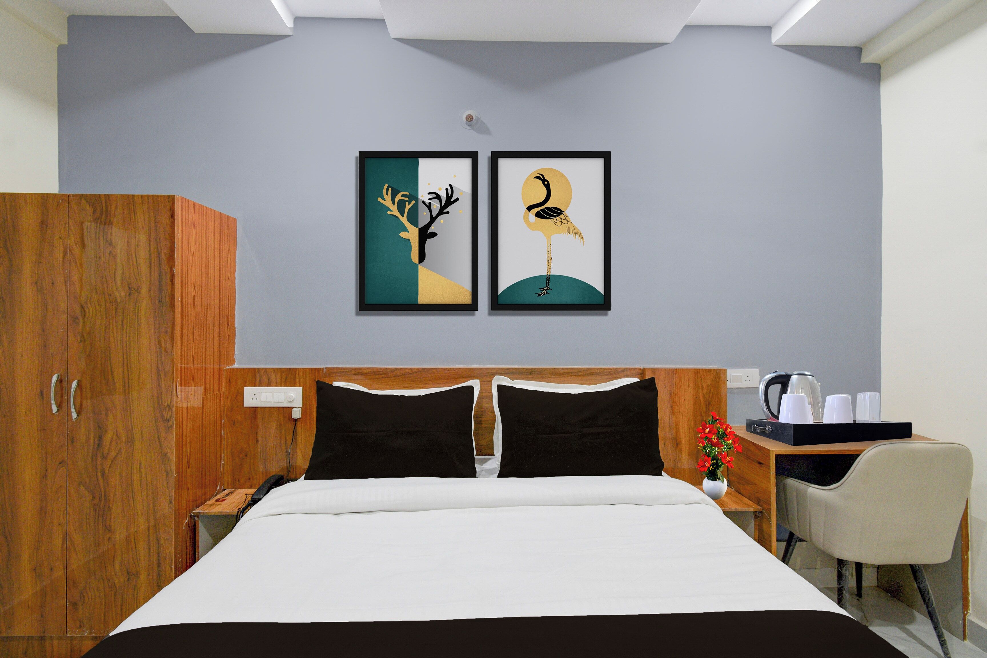 Habitación de hotel con cama, armario, escritorio con silla y dos cuadros en la pared.