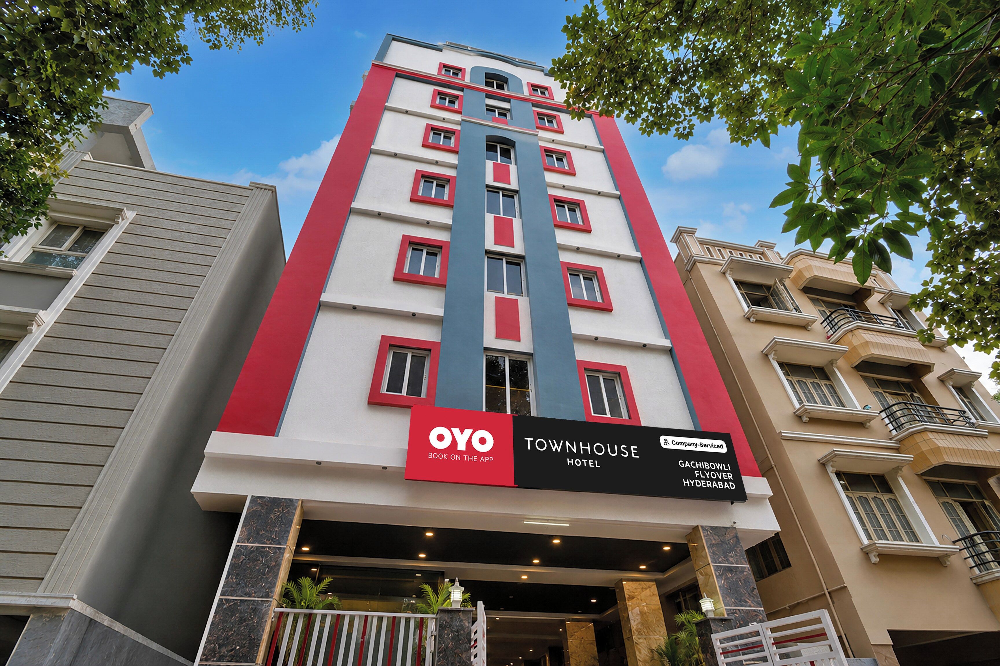 Een meerlaags hotel met een opvallende rode en witte gevel, een bord met de OYO merknaam, en een locatie in Hyderabad.