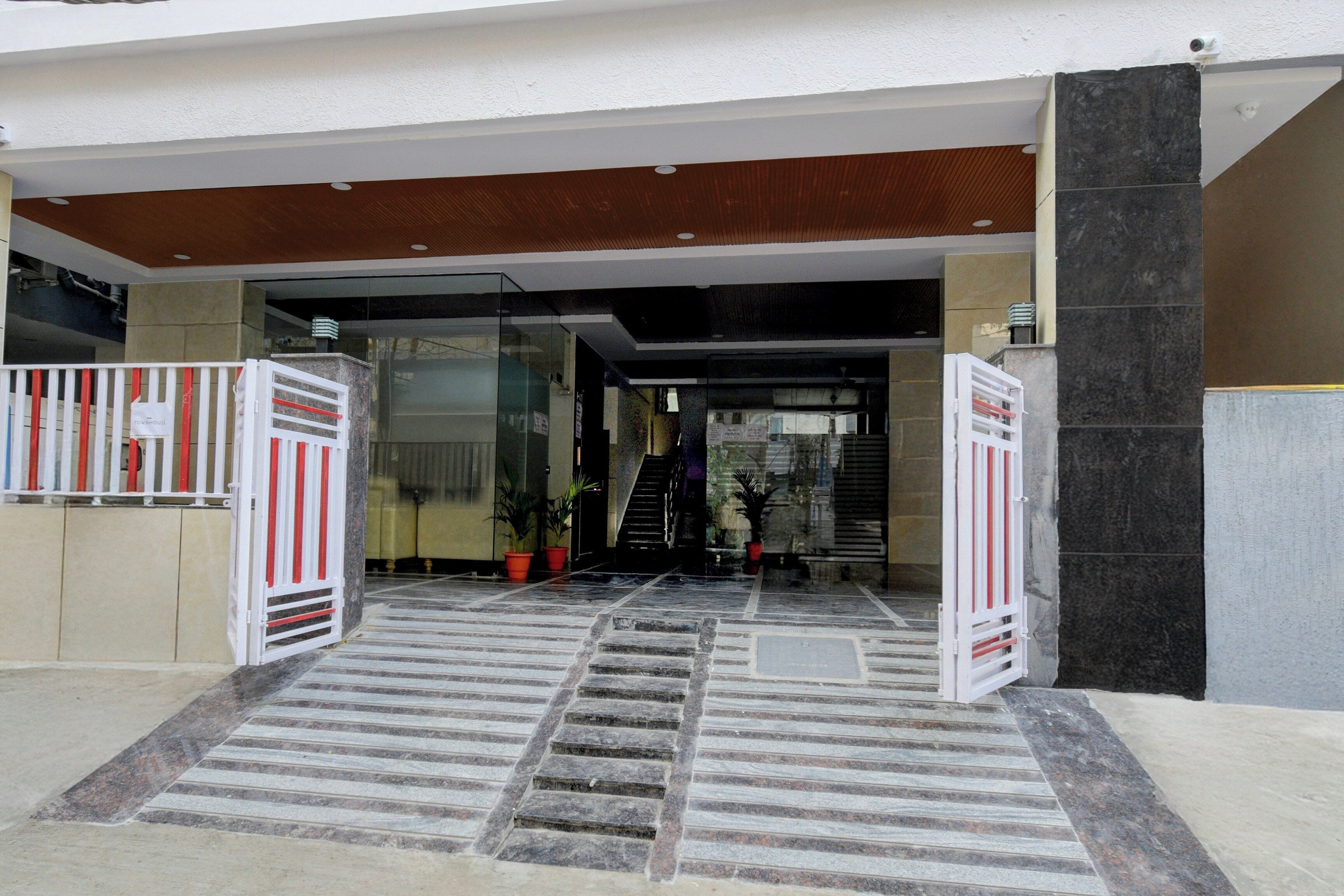 Ingresso di un edificio con porta in vetro, una scalinata e piante in vaso.