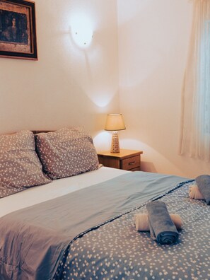 A neatly made bed with a patterned bedspread, a bedside lamp, and a framed picture on the wall. - Hvar spa & Apartments-1 Bedroom-terrace/sea View 3 (Jelsa)