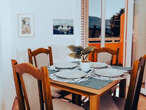 A dining table with four chairs, a potted plant, and two framed artworks on the wall. - Hvar spa & Apartments-1 Bedroom-terrace/sea View 3 (Jelsa)