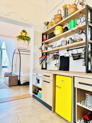 A modern kitchen with wooden cabinets, a yellow refrigerator, and a hanging pot rack. - New Listing (Catania)
