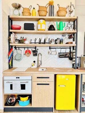 A kitchen with wooden shelves, a yellow refrigerator, and various kitchen utensils. - New Listing (Catania)