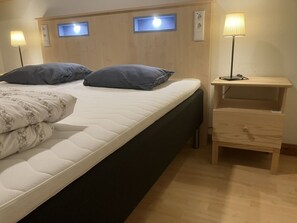 A bedroom with a bed, bedside lamps, a nightstand, and a window. - Holiday Home in Algana With Swimming Pool (Årjäng)
