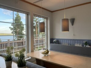 A modern kitchen with a large window overlooking a wooden deck and a body of water. - Holiday Home in Algana With Swimming Pool (Årjäng)