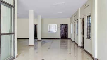 A long corridor with white walls, a tiled floor, and multiple doors and windows.