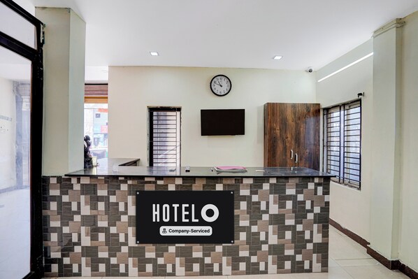 A hotel reception desk with a tiled mosaic design, a clock, and a wooden cabinet.