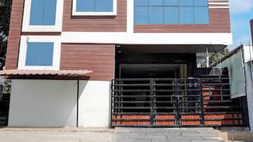 Un edificio de dos pisos con entrada protegida por una reja y una escalera visible que conduce al piso superior.
