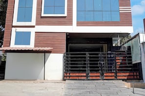 Un edificio de dos pisos con entrada protegida por una reja y una escalera visible que conduce al piso superior.