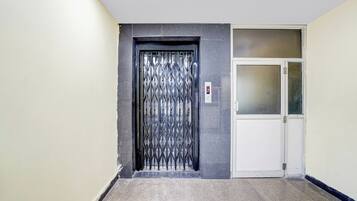 Un pasillo con una puerta metálica y una puerta blanca con paneles de vidrio esmerilado.