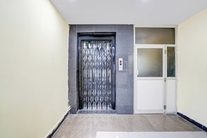 A hallway with a metal gate door and a white door with frosted glass panels.
