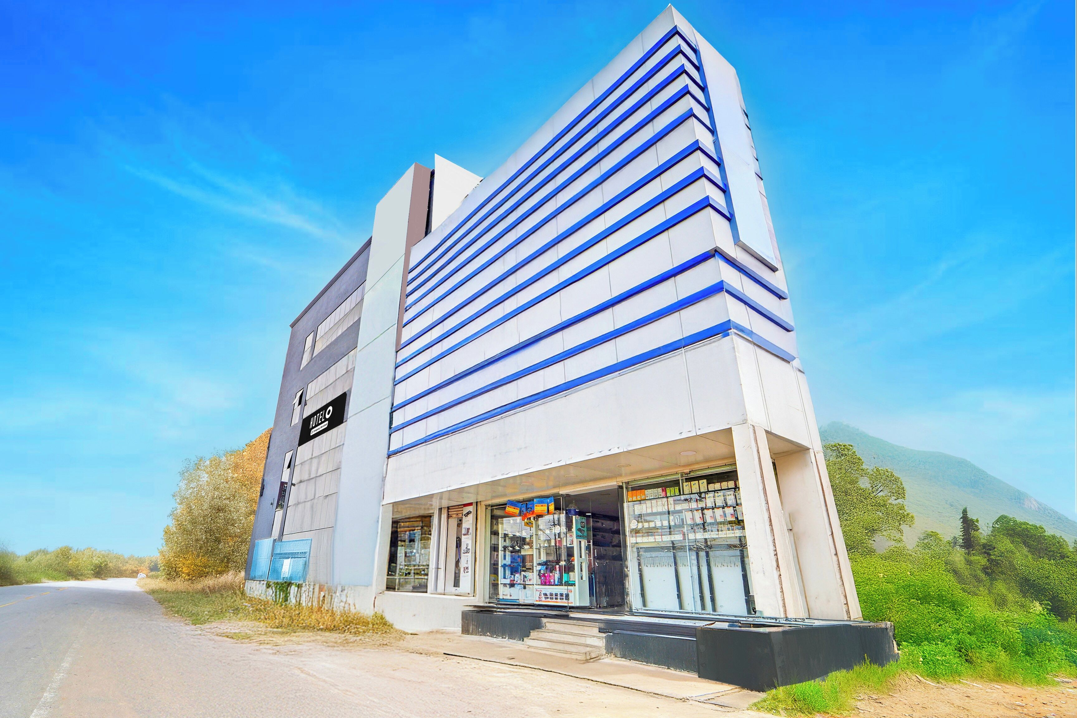 A modern hotel with a prominent 'HOTEL' sign, a visible storefront, and a clear view of the surrounding landscape.