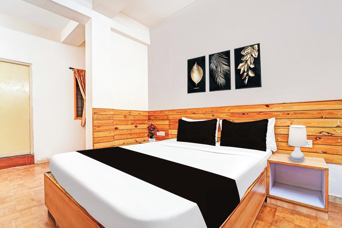 A hotel room with a wooden headboard, a bed with white bedding, a nightstand with a lamp, and wall art.