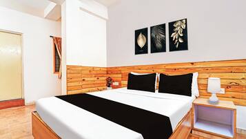A hotel room with a wooden headboard, a bed with white bedding, a nightstand with a lamp, and wall art.