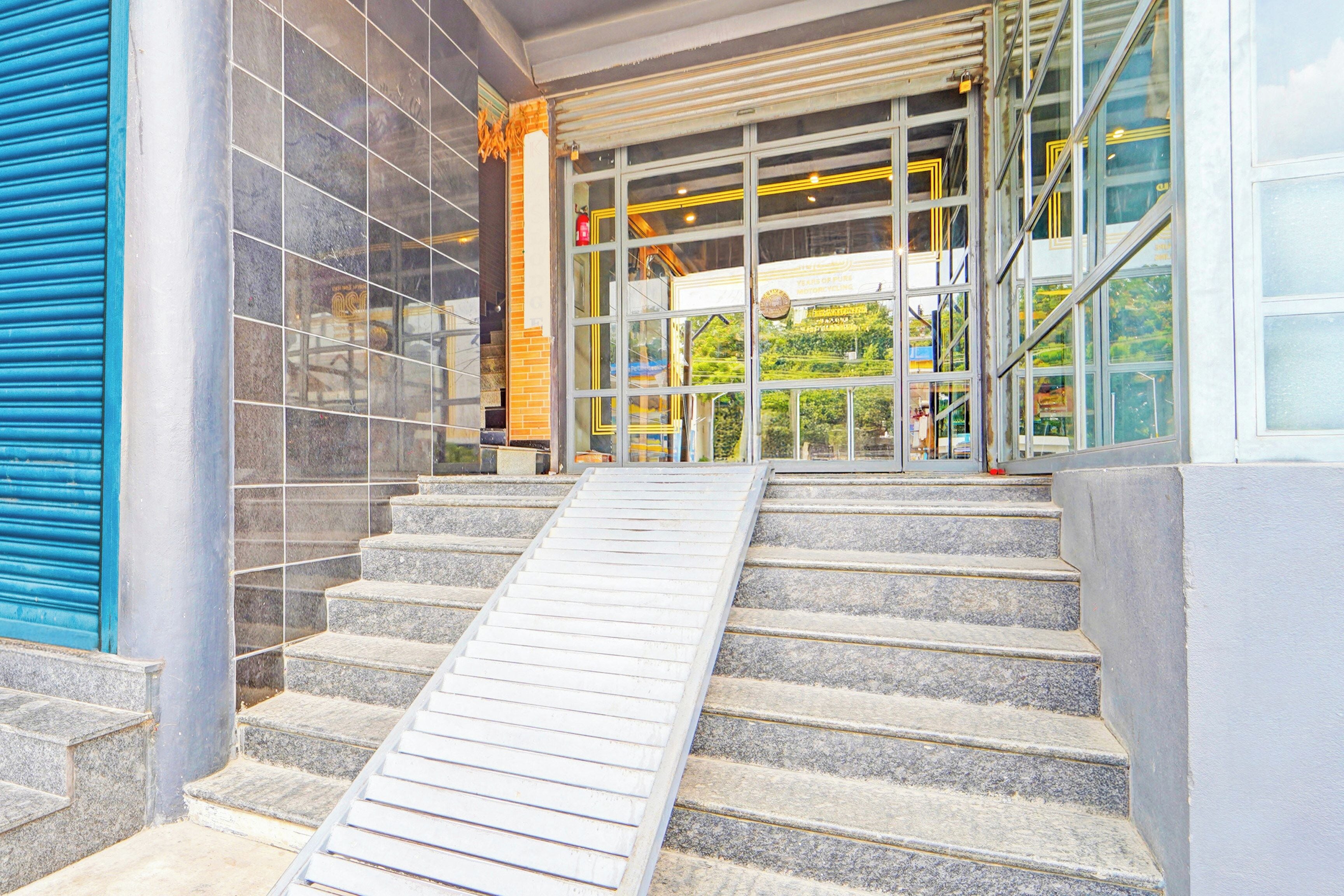 A set of stone steps leading to a glass door entrance with a ramp for accessibility.