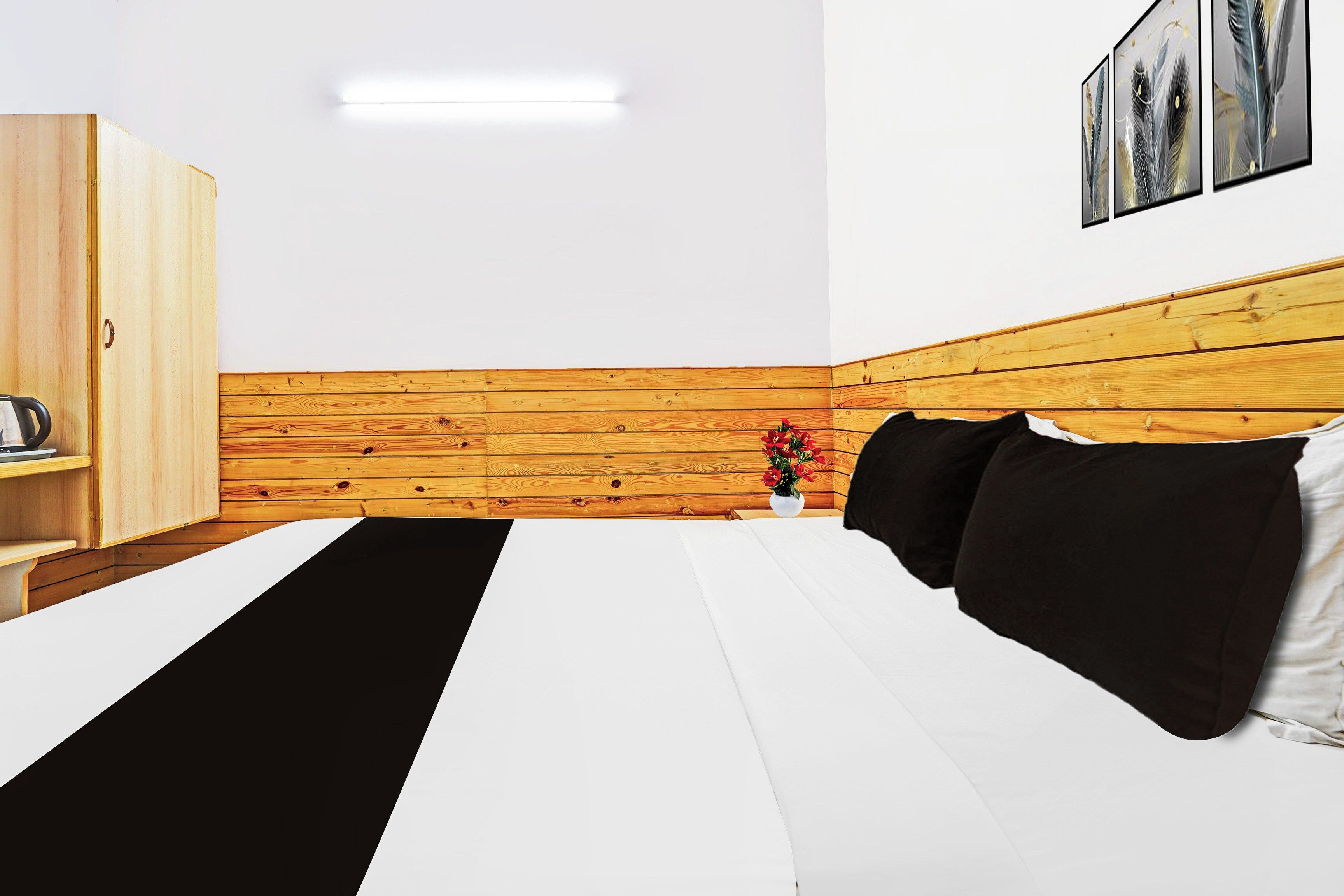 A hotel room with a bed, a wooden wardrobe, a nightstand with a vase of flowers, and a wall-mounted picture.
