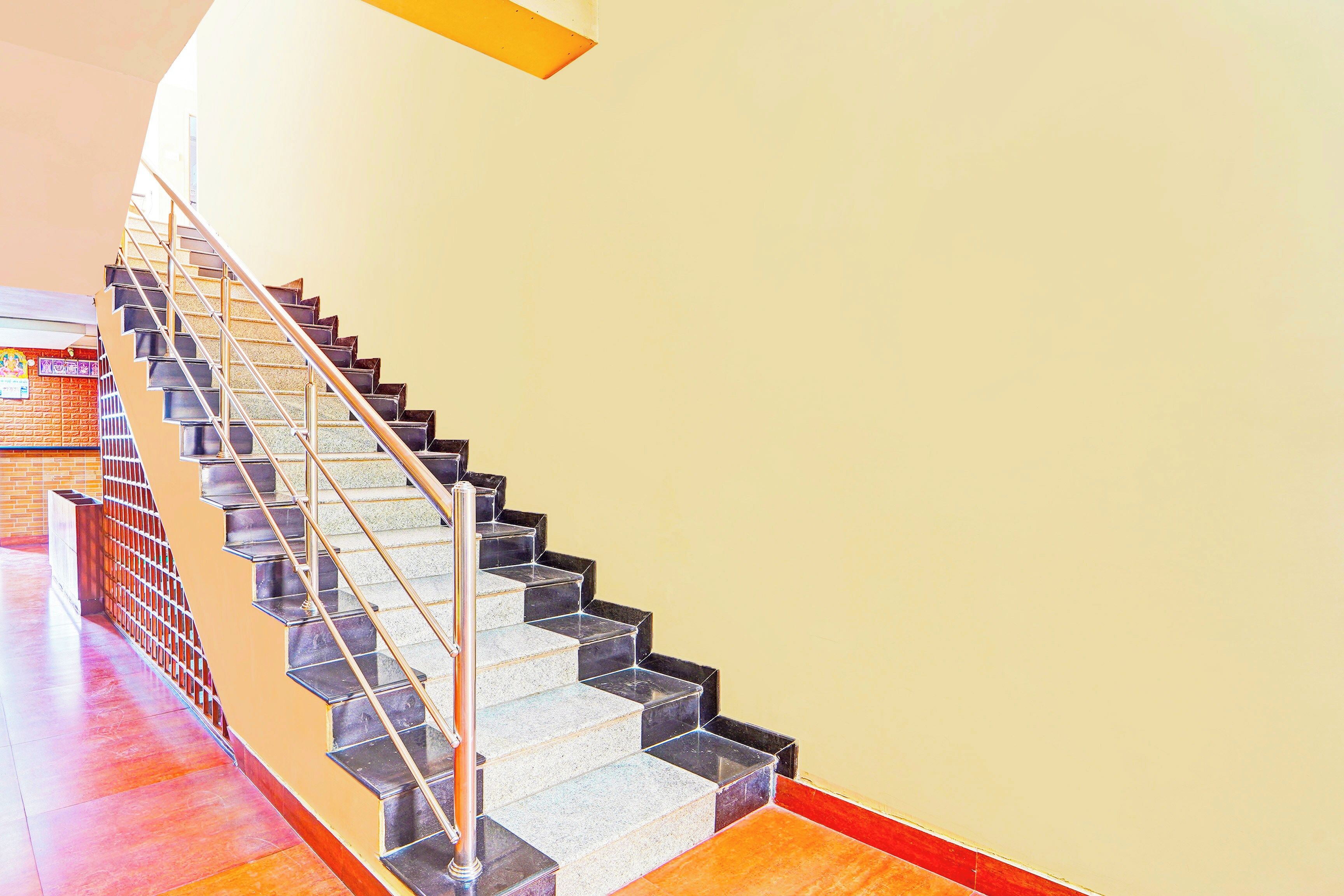 A staircase with a metal handrail and black steps leading to a landing.