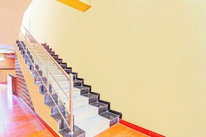 Una escalera con barandilla metálica y peldaños negros que conducen a una plataforma.