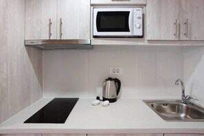 A kitchen with a microwave, kettle, induction cooktop, and stainless steel sink. - Apartment 'Paradise Zante One Bedroom Suite 2' with Shared Pool, Wi-Fi and Air Conditioning (Αγριλιά)