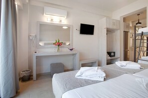 A hotel room with two beds, a desk with a mirror, a TV, and a small bathroom area. - Apartment 'Paradise Zante One Bedroom Suite 2' with Shared Pool, Wi-Fi and Air Conditioning (Αγριλιά)