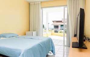 A hotel room with a bed, a television, and a balcony with a view of buildings. - New Listing (Tamandaré)