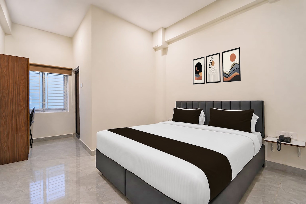 A bedroom with a bed, a wardrobe, a window, and artwork on the wall.