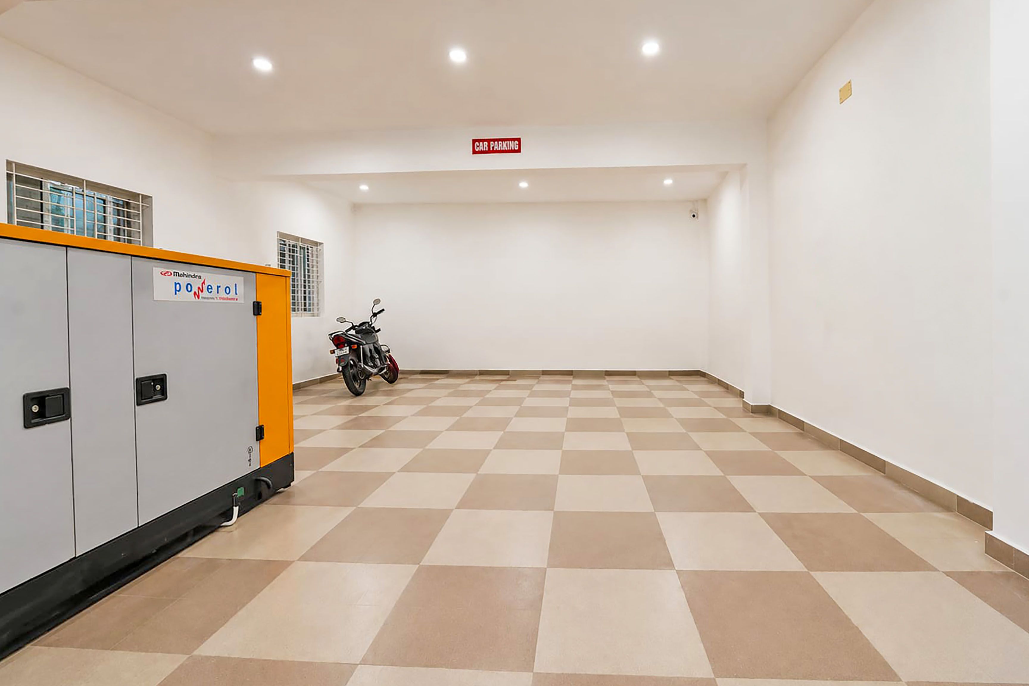 Una habitación limpia y vacía con piso a cuadros, una motocicleta estacionada en un rincón y un letrero que indica zona de estacionamiento para automóviles.