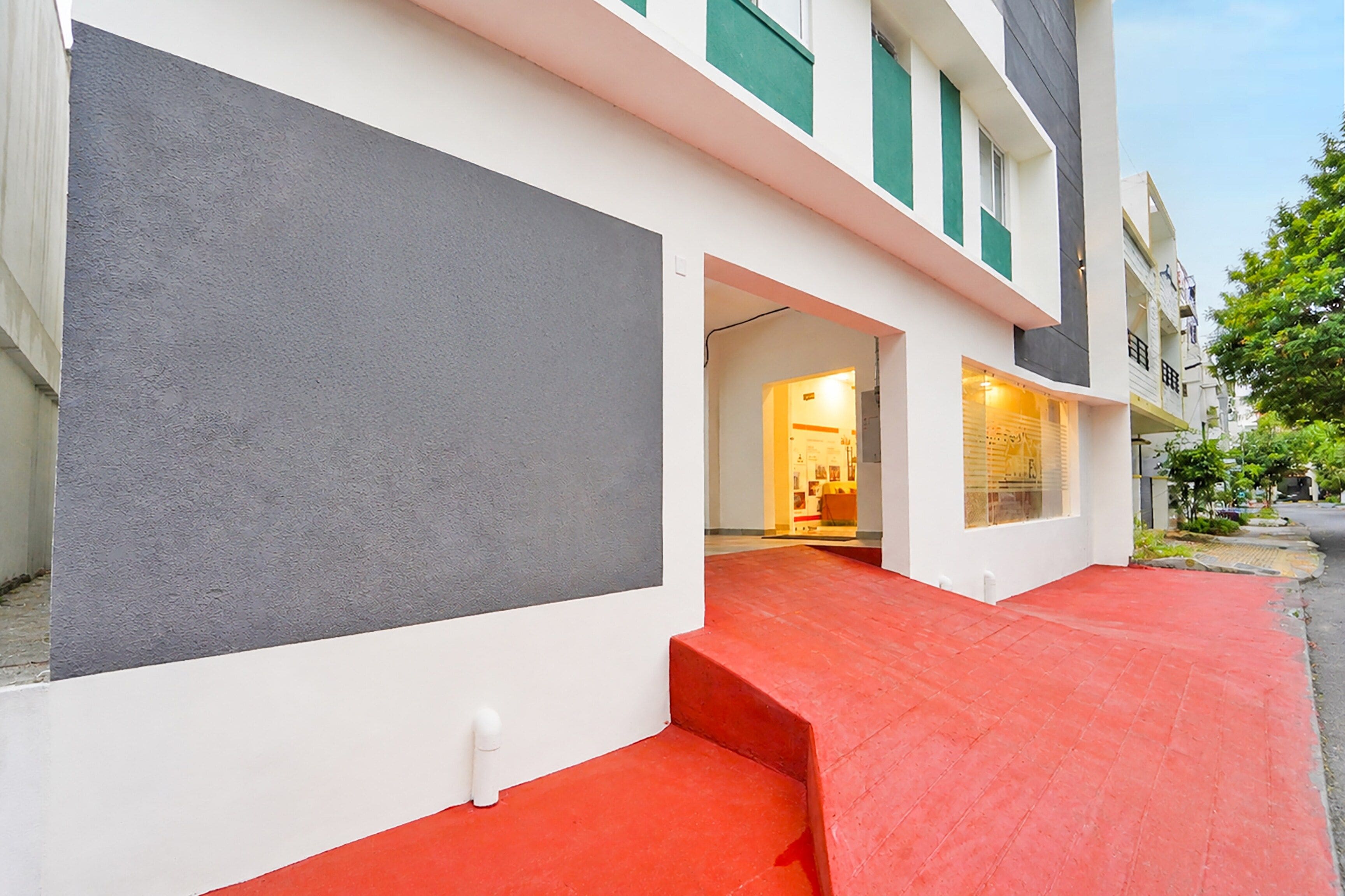 A modern building with a red entrance, white walls, and green accents.