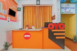 Un mostrador de recepción con el logotipo de OYO, un reloj y un cartel para The New View Hotel.