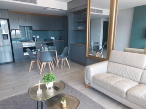 Ein modernes Wohnzimmer mit einer Couch, einem Couchtisch mit Pflanzen und einem Essbereich mit Stühlen und einem Glastisch.
