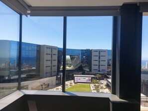 A view from a high-rise window overlooking modern buildings and a small park area. - Luxurious 2-Bedroom Apartment in uMhlanga, South Africa (uMhlanga)