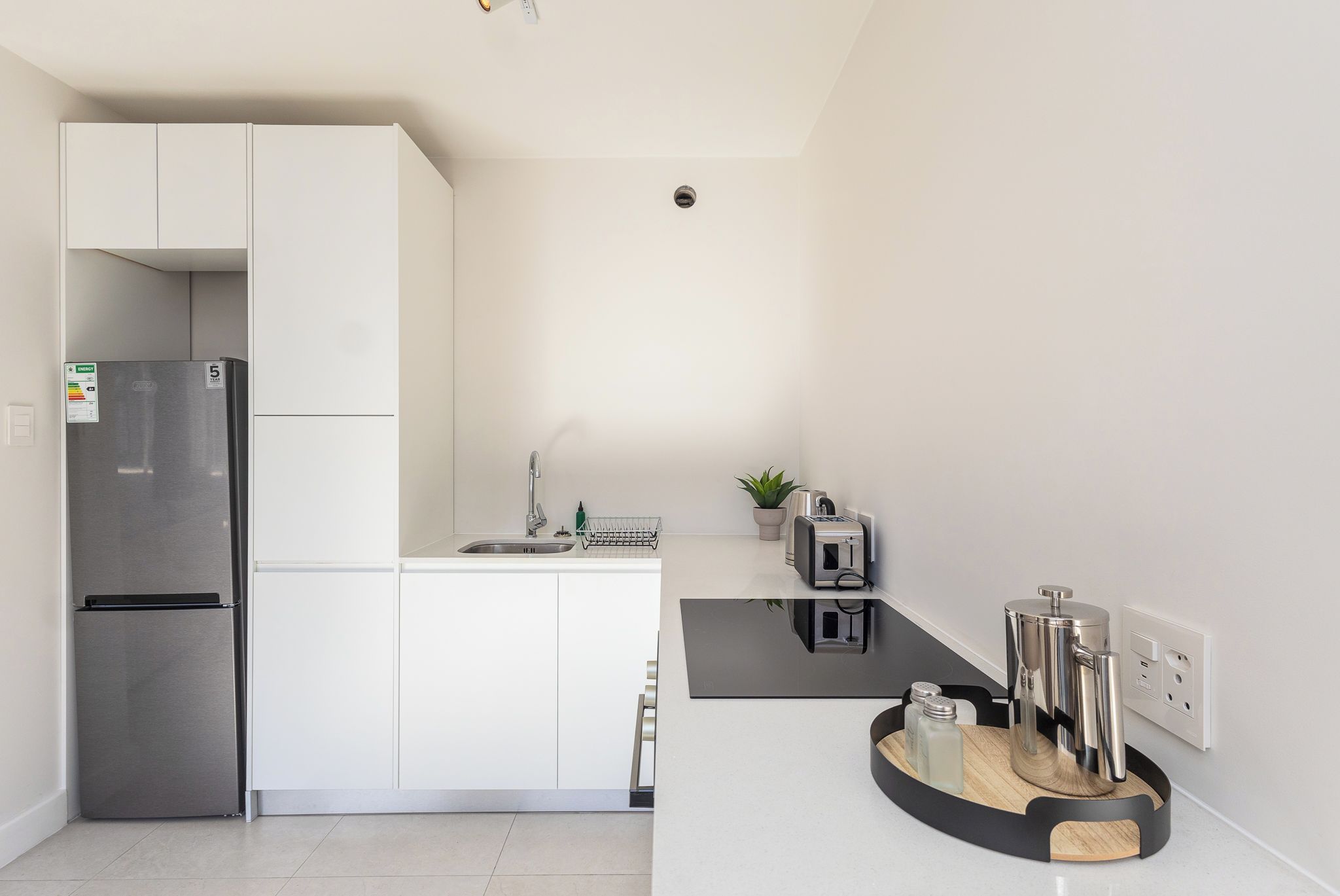 A modern kitchen with a built-in refrigerator, a sink, and a coffee machine.