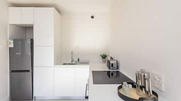 A modern kitchen with a built-in refrigerator, a sink, and a coffee machine.