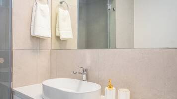 A modern bathroom with a large white sink, a mirror, and two white towels hanging on towel rings.