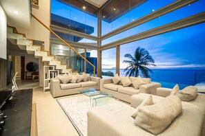 A modern living room with a large glass wall overlooking the ocean, a staircase, and a pool. - Kamala Beach frontline sea view villa (Kamala, Kathu District,)